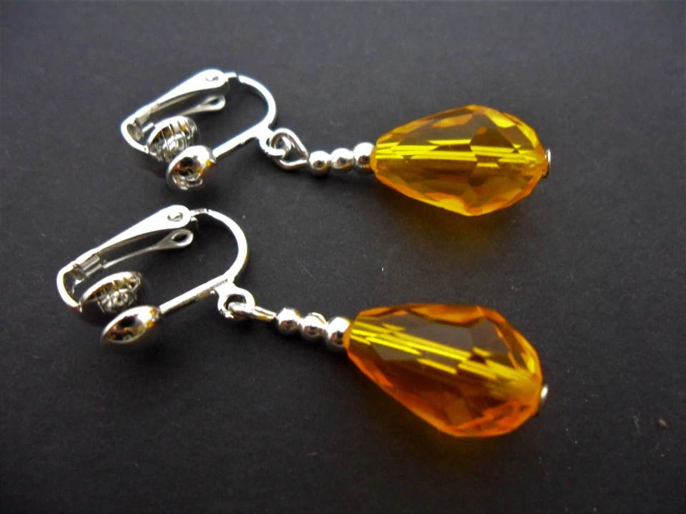 A PAIR OF ORANGE/AMBER GLASS CRYSTAL DANGLY TEARDROP CLIP ON EARRINGS. NEW. - Image 1 of 1