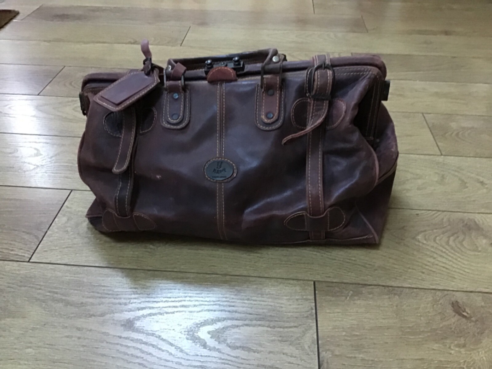 Brown leather luggage holdall ith luggage tag clasp and strap closure
