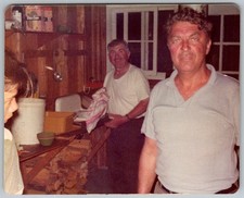 Vtg Color Snapshot Two Men in Rustic Cabin Kitchen Woodpile Dixie Cups 1970s