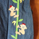 Blue denim kids’ 2-piece outfit with embroidered monkeys climbing green leaves, red headscarf, and yellow banana accents.