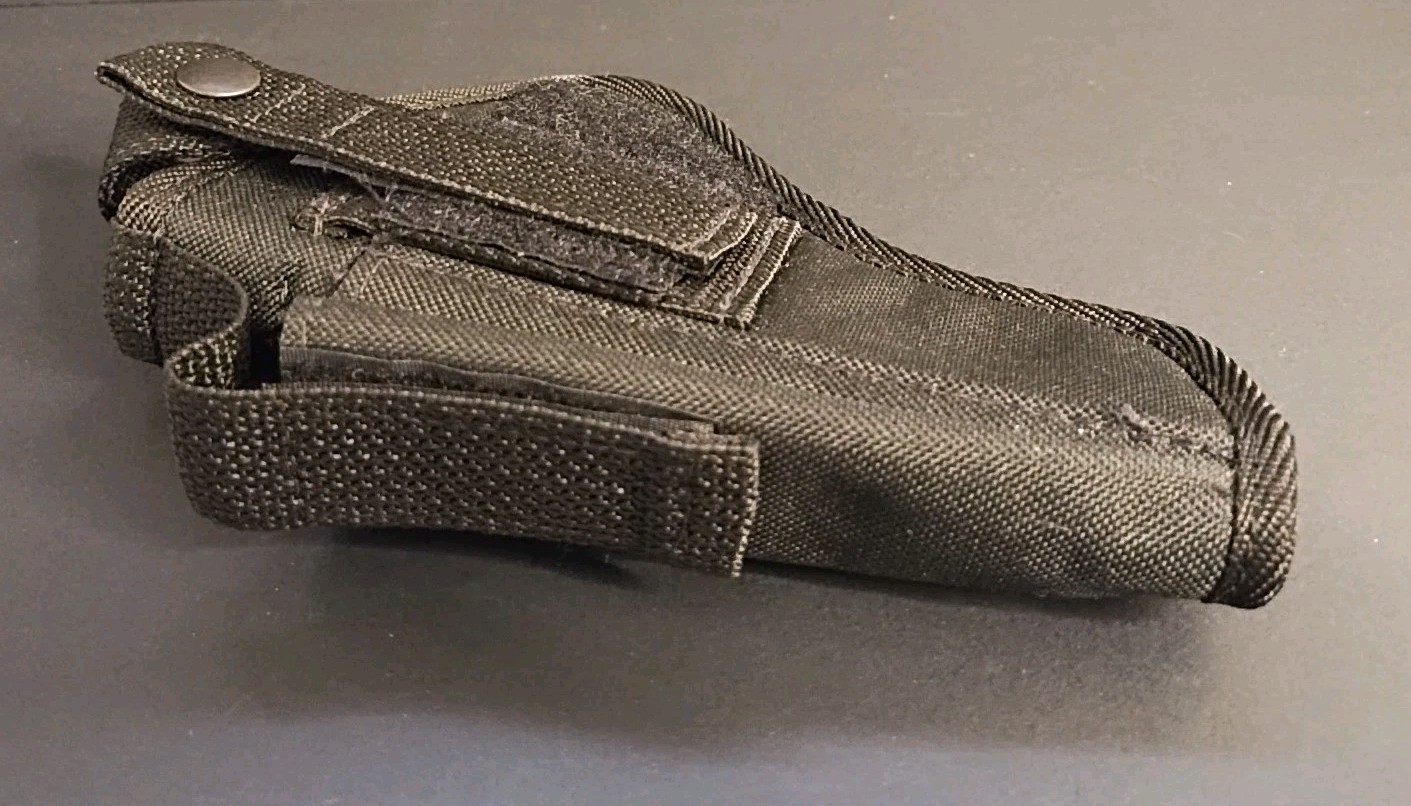 Black nylon IWB holster with textured grip, double stitching, and visible magazine holder on a gray surface.