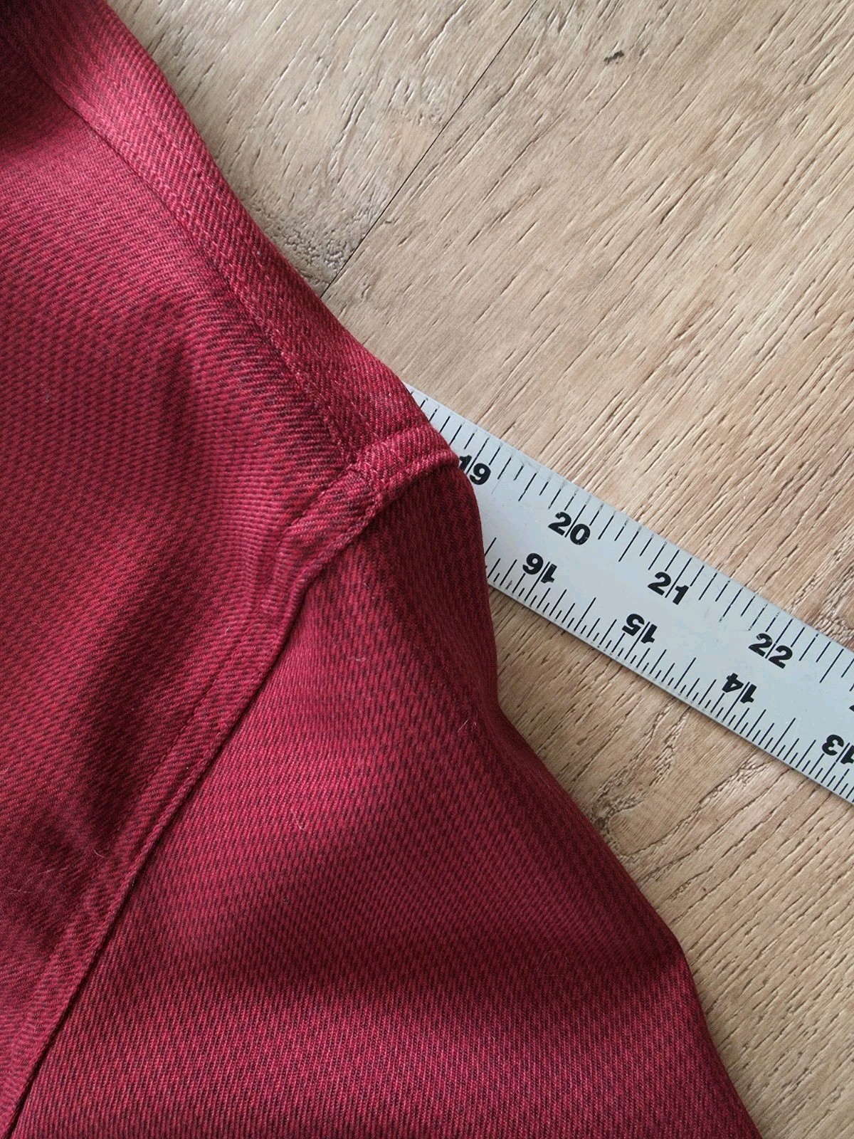 Red Filson virgin wool guide shirt with textured knit, measuring 2 inches along the seam on a light wood floor.