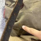 Brown canvas crossbody bag with front zipper pocket, tan leather strap, and visible red “Frost River” label on side.