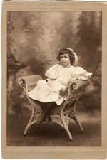 AN ADORABLE LITTLE GIRL SITTING IN A WICKER CHAIR : CABINET CARD