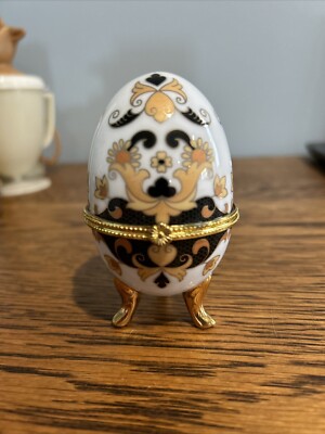 Porcelain egg shaped trinket box.  Gold and black scroll pattern.  Measures appr