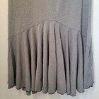 Grey maxi skirt with vertical tiered flow, scalloped trim, and small black fringe detail near hem.