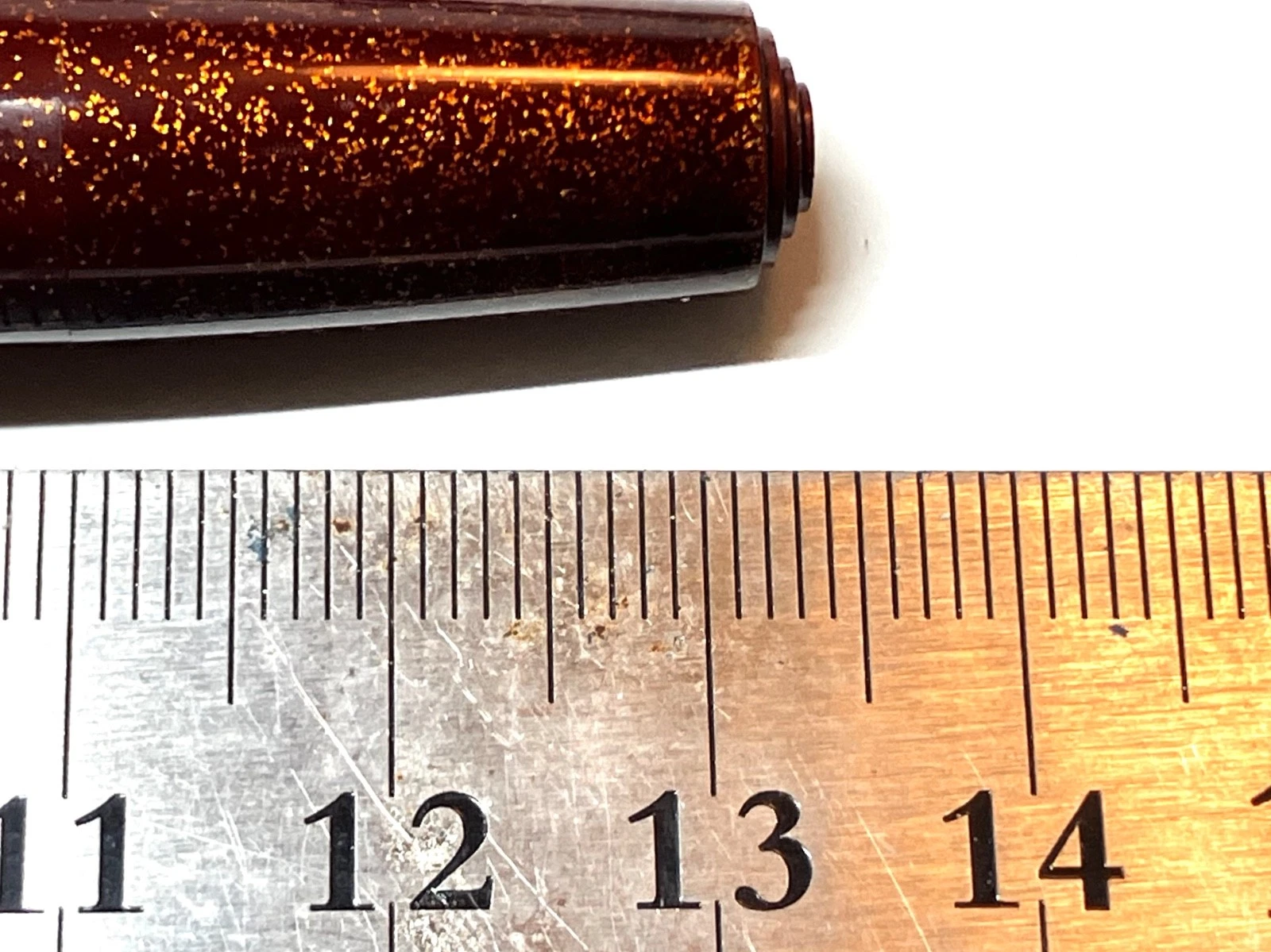 Vintage ink shut off fountain pen with gold-toned barrel, shown beside a metal ruler on white paper with black text.