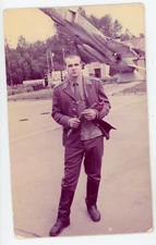 PHOTO photograph, a soldier poses in front of an airplane military base