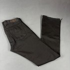 Black faded bootcut jeans with back pocket and brown leather patch on waistband, folded on light gray surface.