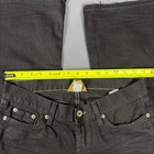 Black faded bootcut jeans with white stitching, front pockets, and visible yellow measuring tape across the waistband.