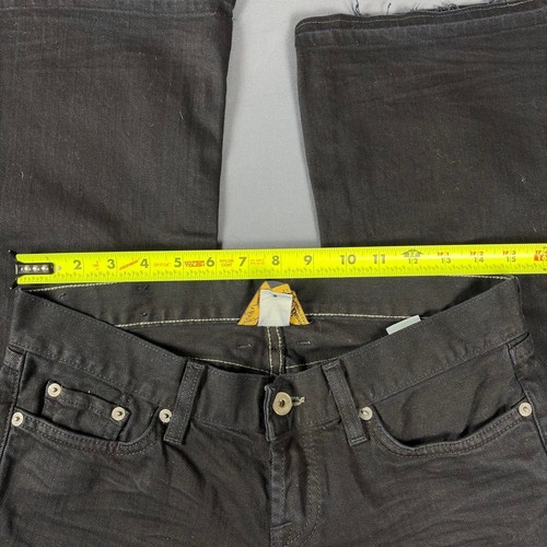 Black faded bootcut jeans with white stitching, front pockets, and visible yellow measuring tape across the waistband.