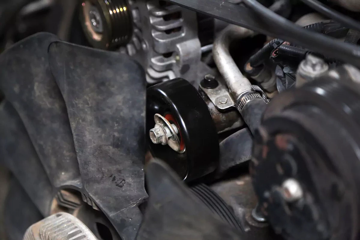 The new idler pulley is installed on the engine. The idler pulley bolt needs to be tightened.