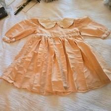 Vintage Baby Girl Dress Characterized by Its Pale Peach Color