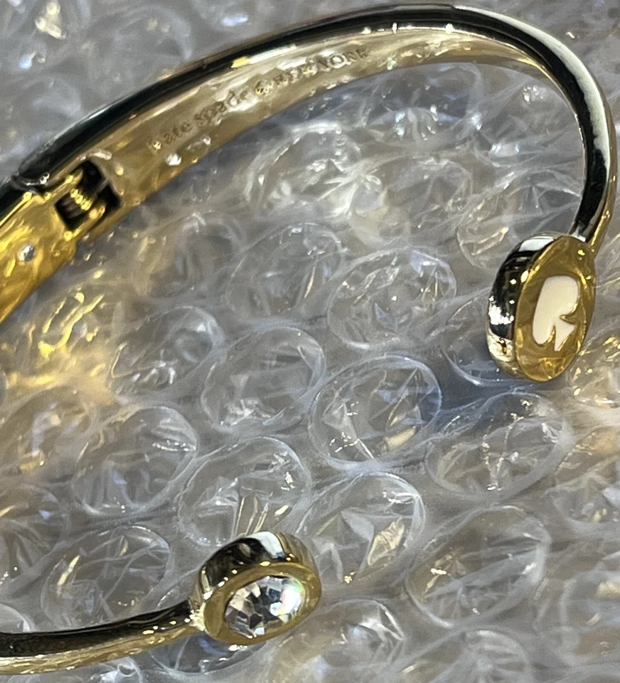 Brazalete Kate Spade New York dorado con bisagras con pala blanca y estrás transparente Foto 3 de 4
