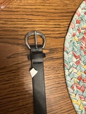 black leather belt with a round silver-tone buckle.