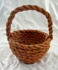 Small, woven natural fiber basket with twisted handle