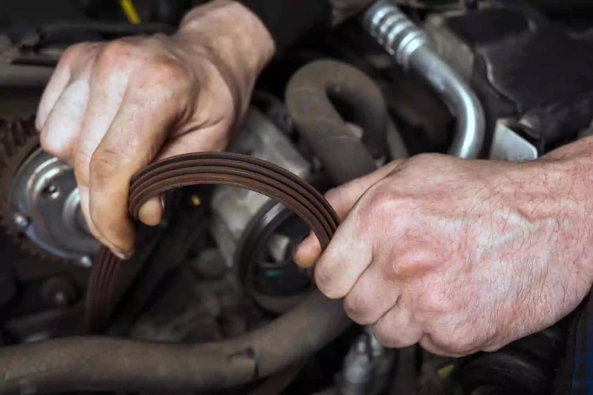 Mechanic installing a new serpentine belt on an alternator.