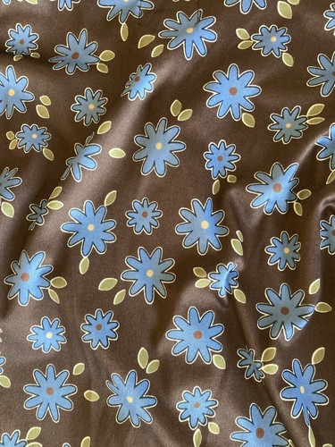 Brown fabric with blue and yellow flower print, green leaves, USA Made label at bottom.