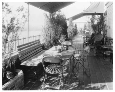 Tree-lined patio overlooking river; canvas awning, table in foregr- Old Photo