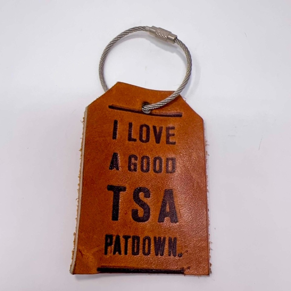 A leather luggage tag printed with a TSA pat-down joke — vintage feel, actually useful on a bag, and guaranteed to get a laugh at the airport carousel.