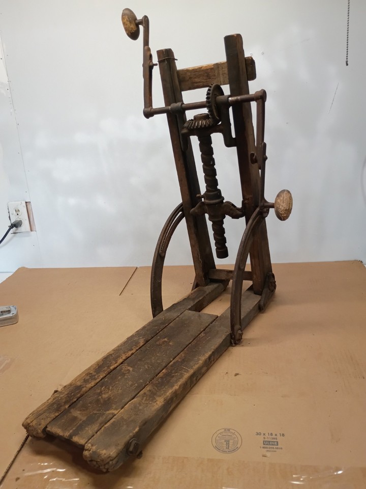 A hand-cranked timber-frame drill boring machine from the pre-electric era — a heavy, mechanical, brutally purposeful antique that looks incredible displayed in a workshop or library.