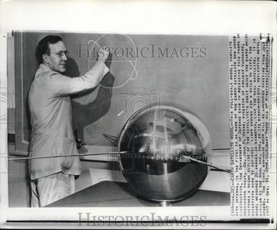 1956 Press Photo Dr. John Hagan sketches orbit with earth satellite model in DC