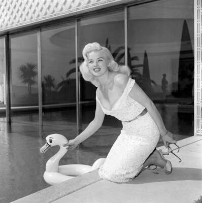 Diana Dors an inflatable swan as she poses by a swimming pool cann- Old Photo
