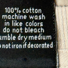 White printed inner label of Y2K VTG T&C surf shirt with black text, laundry instructions, and yellow floral accents.