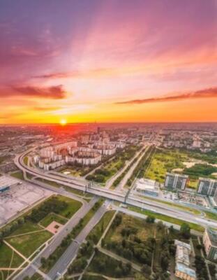 Wandbild: Heller Sonnenuntergang über der Stadt, Luftblick aus einer Höhe [...]