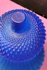 Cobalt blue glass tulip-shaped votive candle holder with textured diamond pattern, made in the USA on pink surface.