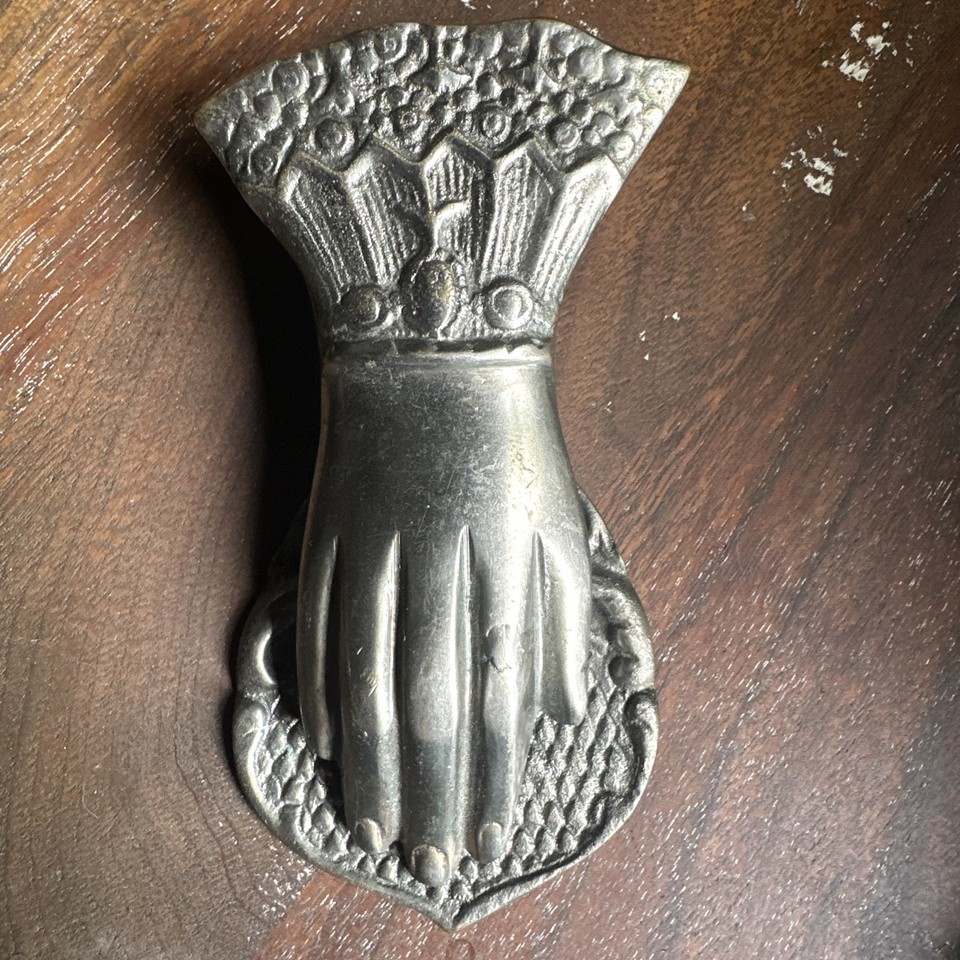 A 6-inch antique brass engraved hand-shaped paper clip holder — sculptural, weird, and absolutely unforgettable on any desk.