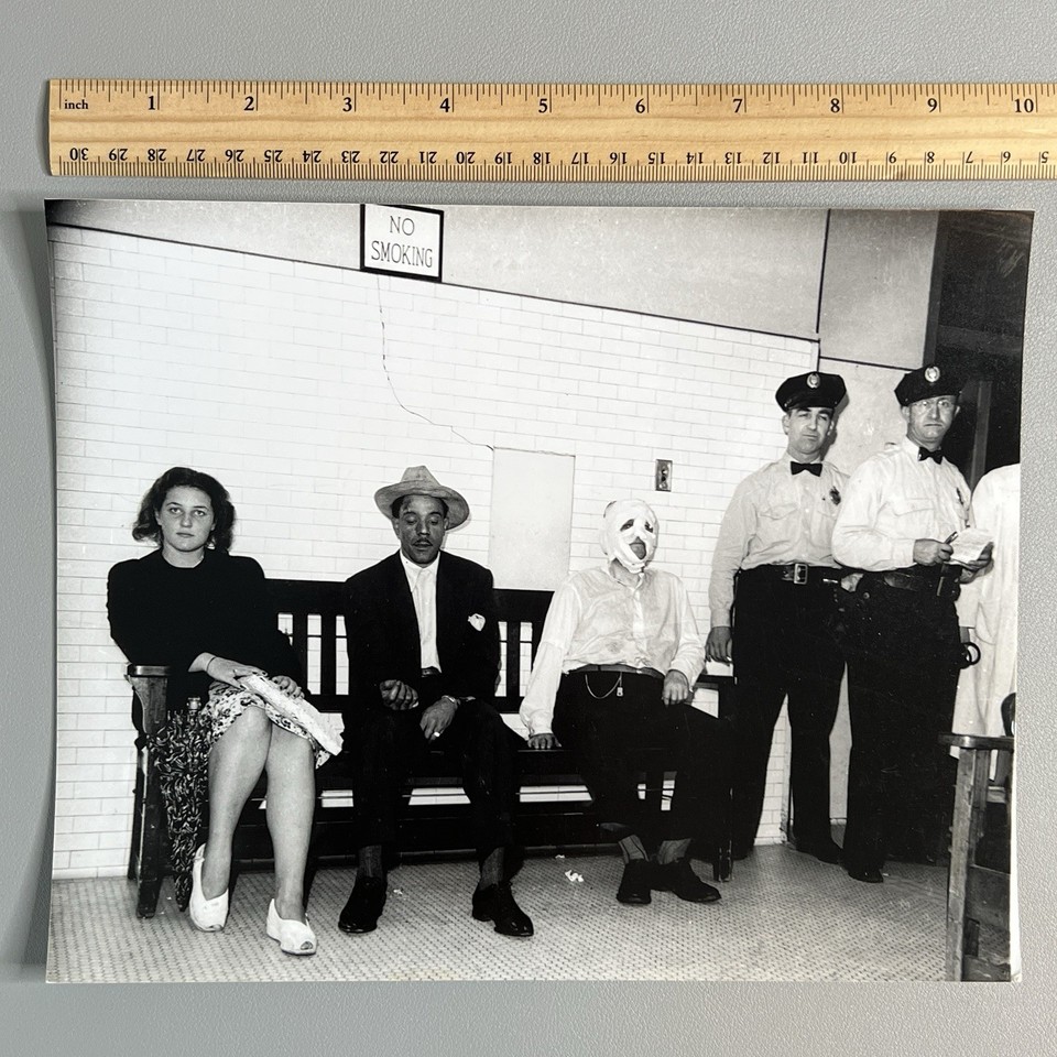 A genuine 1940s crime-scene-style photo in the gritty Weegee tradition — a bandaged mummy-like figure straight out of noir pulp fiction that belongs framed in a dark-academia study.