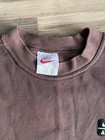 Brown vintage Nike sweatshirt with white tag, red swoosh, and black square graphic on chest, made in USA.