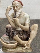 This is a vintage Capodimonte hand-painted porcelain figurine/seated fisherman
