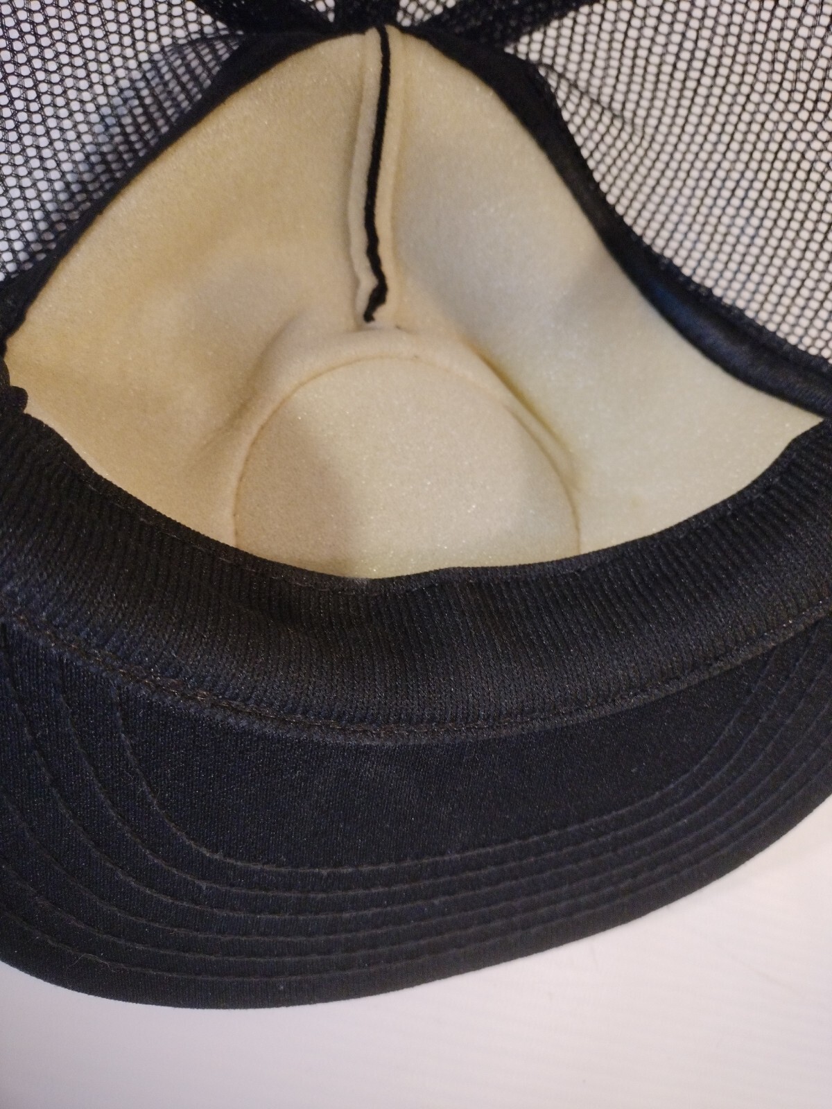 Black trucker hat with tan interior lining, snapback closure, and “Made in USA” text on the side.