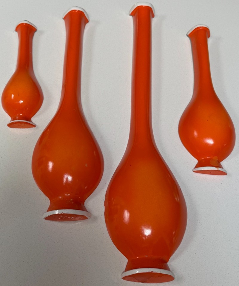 A set of orange chalkware bottle wall hangings straight out of a 1960s rec room — bold color, funky silhouette, and genuine vintage charm.