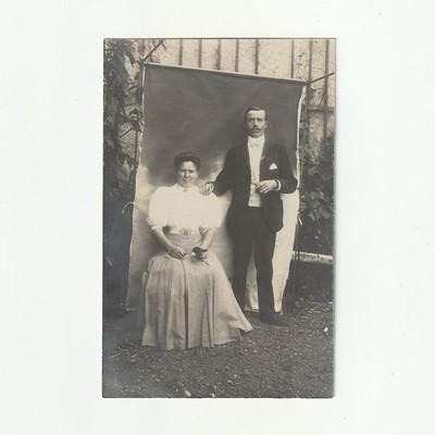 Eine Frau und ein Mann - bemalter Hintergrund und Gartenmauer - Fotokarte ca 1910