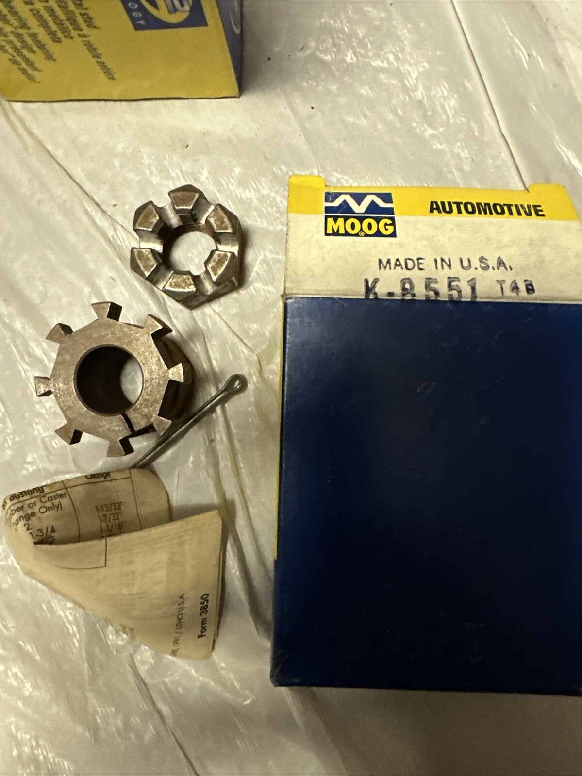 MOOG K8551 adjustable camber and caster kit with worn blue box, yellow MOOG Automotive label, and two metal adjusting parts.