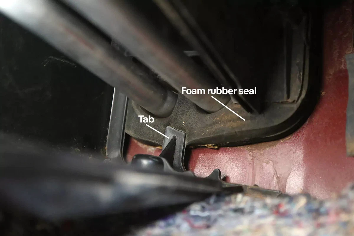 A closeup view with callouts to the foam rubber seal and tab of the heater core cover.