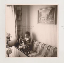 Woman in the Corner of Room, Reading a Book on the Sofa with a Cigarette in Hand