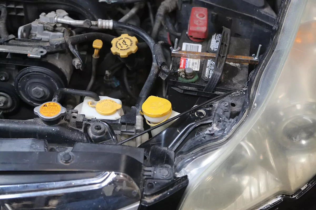 A vehicle's windshield fluid reservoir with its yellow cap closed.
