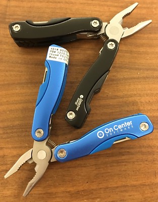 Pair of multi tools, one blue, the other black, with sheaths. Camp, hunt, crafts