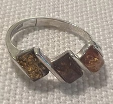 Silver ring features three distinct, multi-colored Baltic amber stones.