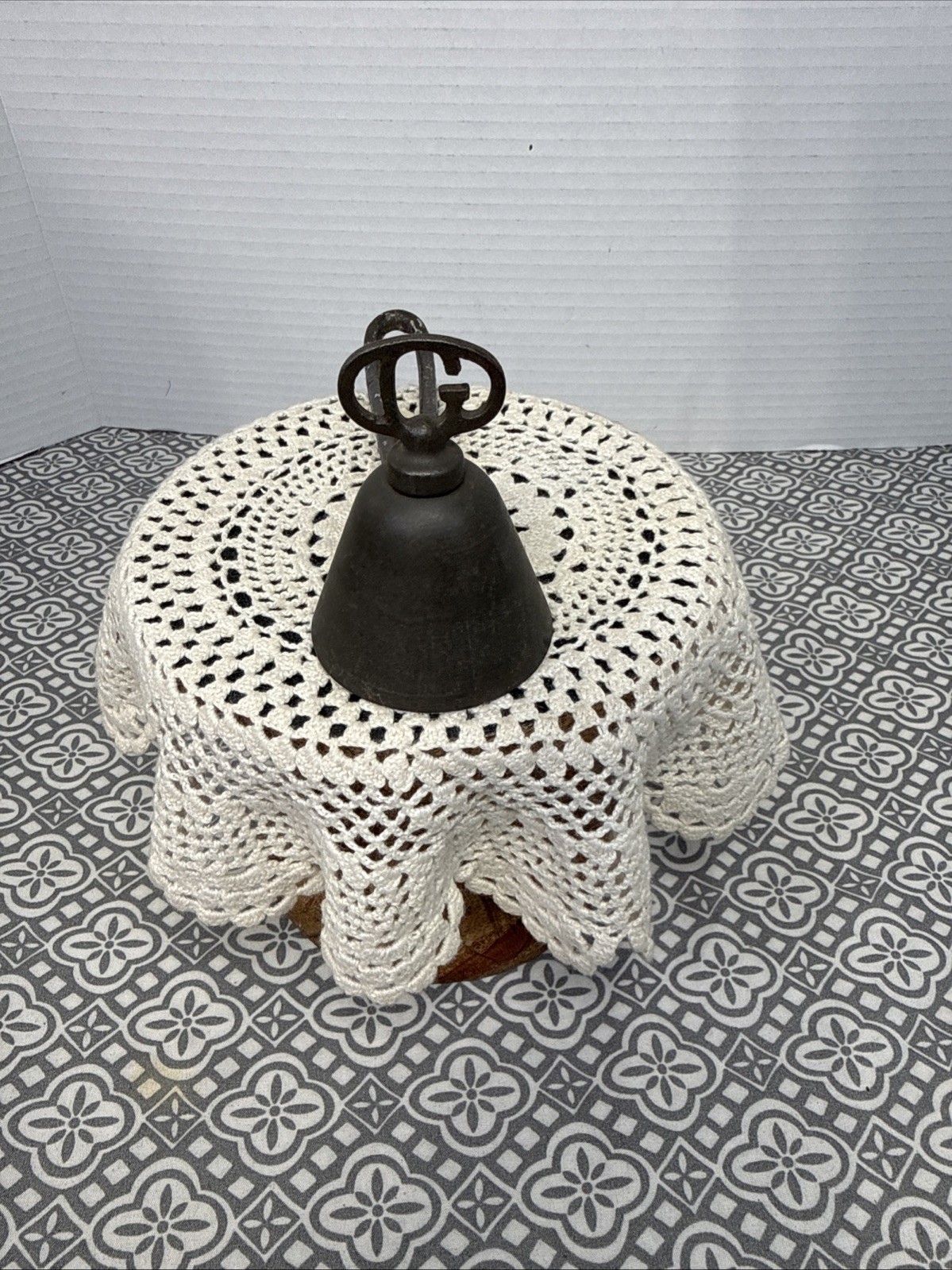 Antique silver Gilchrist Turnkey Type ice cream scoop with black metal bowl and white lace-patterned tablecloth.