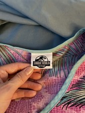 Jurassic World Dominion Women’s V-Neck Scrub Top Pockets Purple/Blue Floral