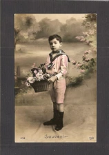 HAND-TINTED REAL-PHOTO POSTCARD:  YOUNG BOY WITH BASKET OF FLOWERS - Mailed 1912