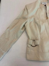 Cream blazer with high collar and decorative metal circles on the sides.