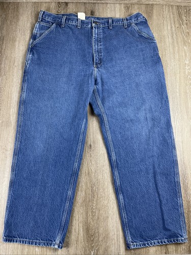 Blue denim Y2K Carhartt men’s carpenter jeans with faded thighs, front pockets, and white-metal rivets on a light wood floor.