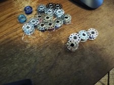 lot of 17 metal 10 hole and 2 plastic 1 hole sewing bobbins most with thread