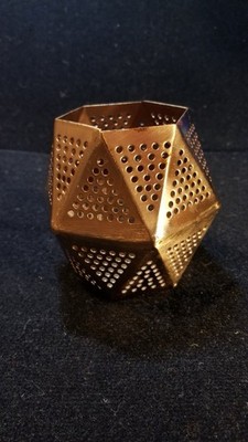 The candle holder in the image is likely a Tom Dixon Etch Tealight Holder.